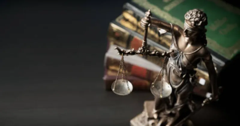 Estatua de la justicia con una balanza, delante de varios libros